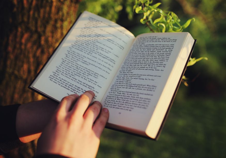 Livre d’occasion tenu dans les mains en extérieur, symbole d’une lecture écologique, solidaire et respectueuse de la planète. 