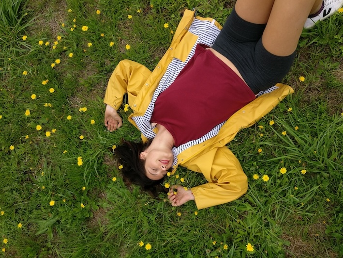 Personne allongée dans l’herbe parmi des pissenlits en fleurs, plante connue pour ses bienfaits naturels.