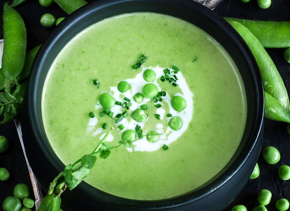 Bol de soupe veloutée de pois cassés vert vif avec touche de crème et ciboulette